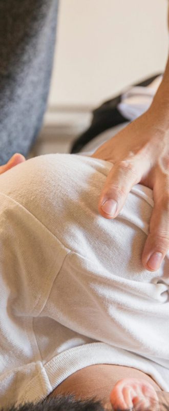 Crop anonymous medical specialist rubbing shoulders of male client lying on couch in medical salon