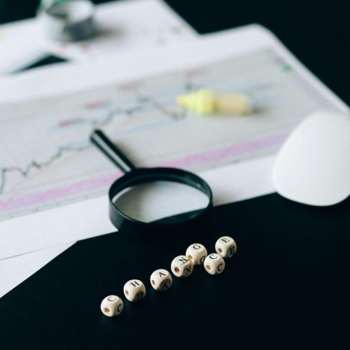Conceptual still life of business documents, charts, and magnifying glass focusing on risk analysis.