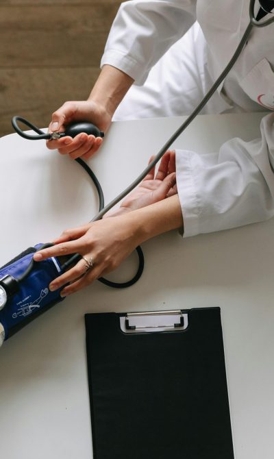 A medical practitioner checks a patient's blood pressure in a clinical setting, showcasing healthcare service.