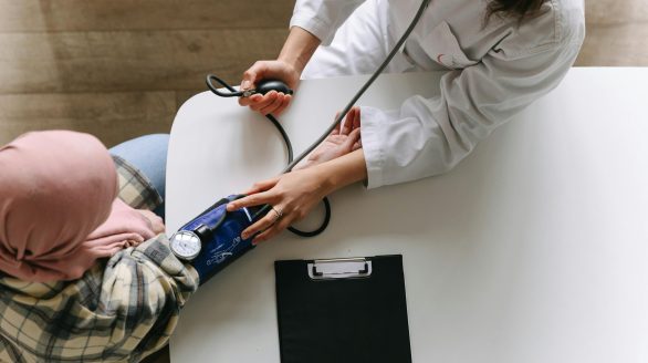 A medical practitioner checks a patient's blood pressure in a clinical setting, showcasing healthcare service.